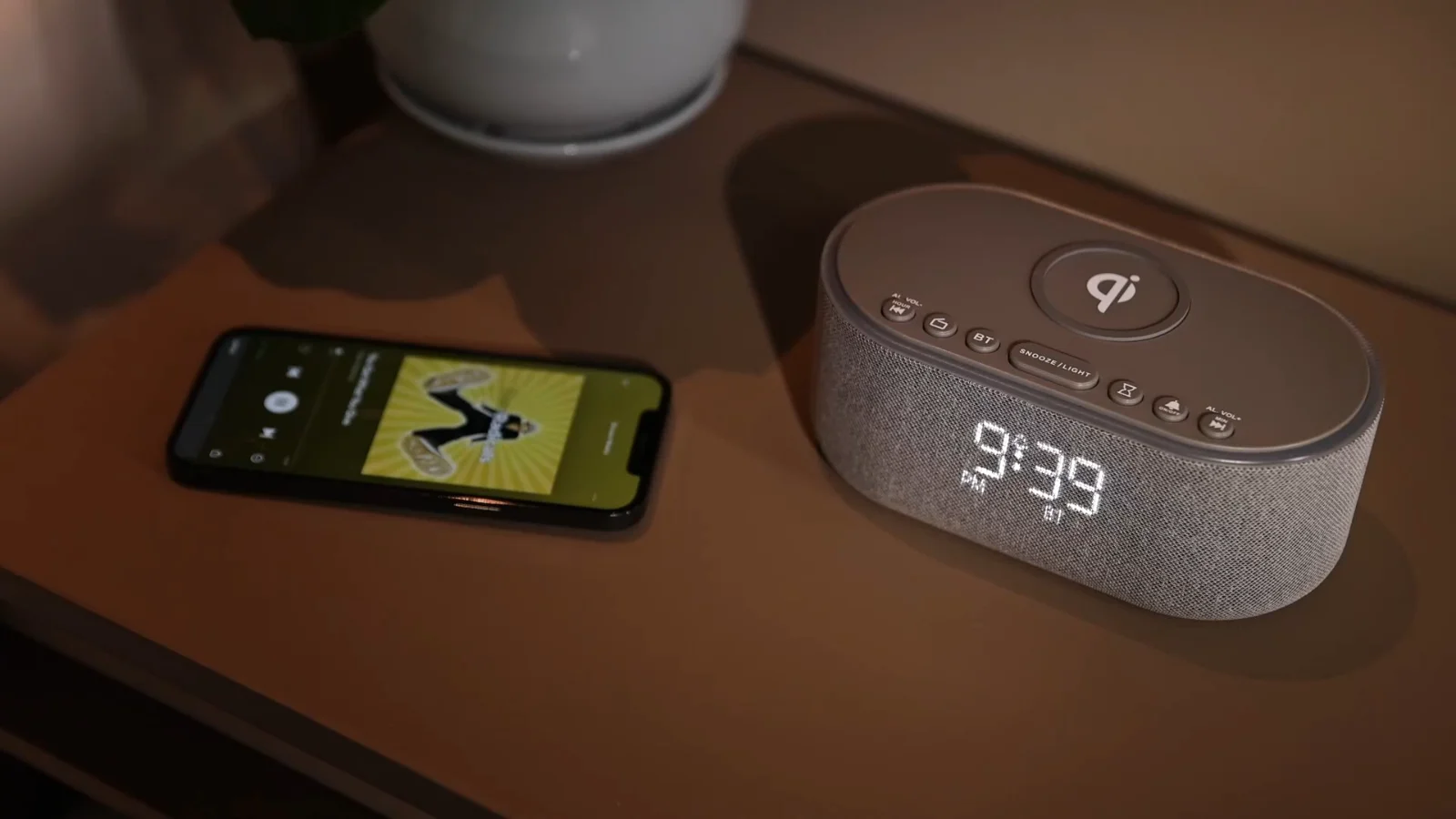 A phone charging on a UE268 clock radio beside a bed